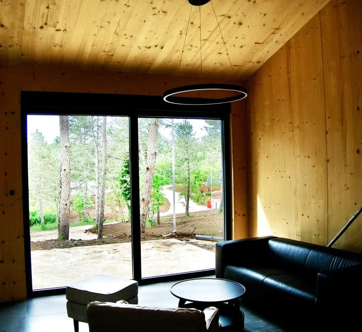 The timber-lined living room of a finished house at Citadel.Garden, its sliding glass wall opening onto the pines outside
