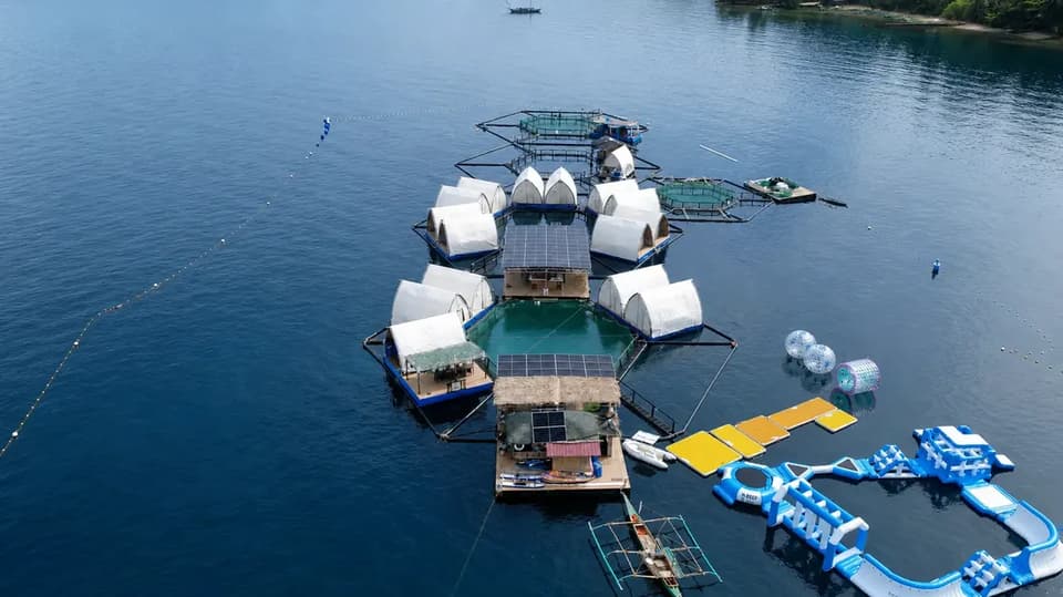 The Reef Resort from the air, with the thatched service deck, solar roofs and the water park in the foreground and outrigger boats alongside