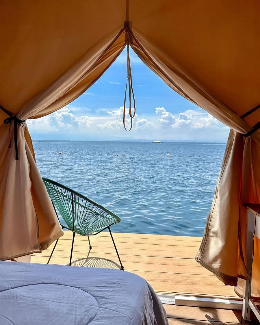 The deck of a glamphouse at the Reef Resort, a chair at the tent opening looking out over the water