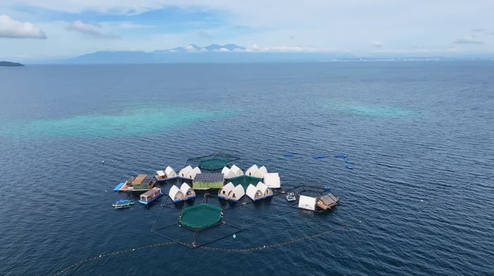 The Reef Resort cluster in the Davao Gulf, with the reef shallows beside it and the mainland mountains on the horizon