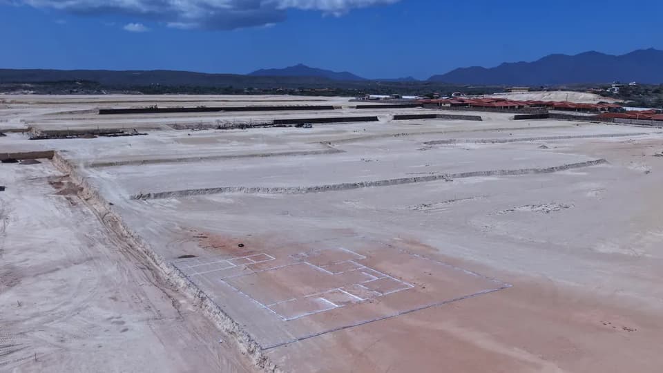 The outline of the first house marked out in white on a levelled terrace, with the finished terraces and the neighbouring houses beyond