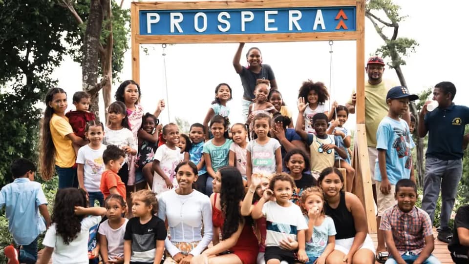 Children and families gathered under the Próspera sign on Roatán