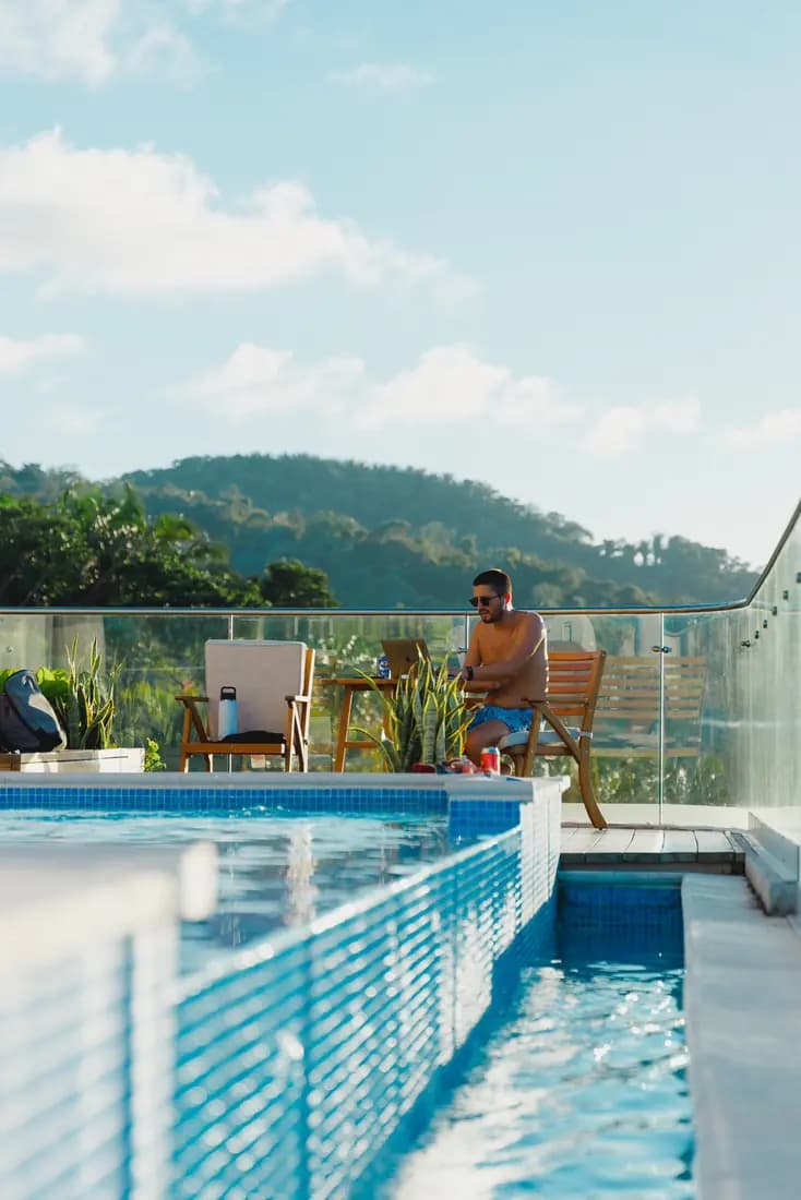 A resident by a hillside pool overlooking the hills at Próspera