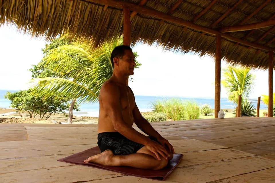 Yoga under a thatched palapa looking out over the shore