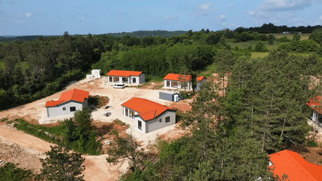 Aerial view of the Citadel.Garden village in Istria, orange-roofed houses on a cleared plot ringed by woodland