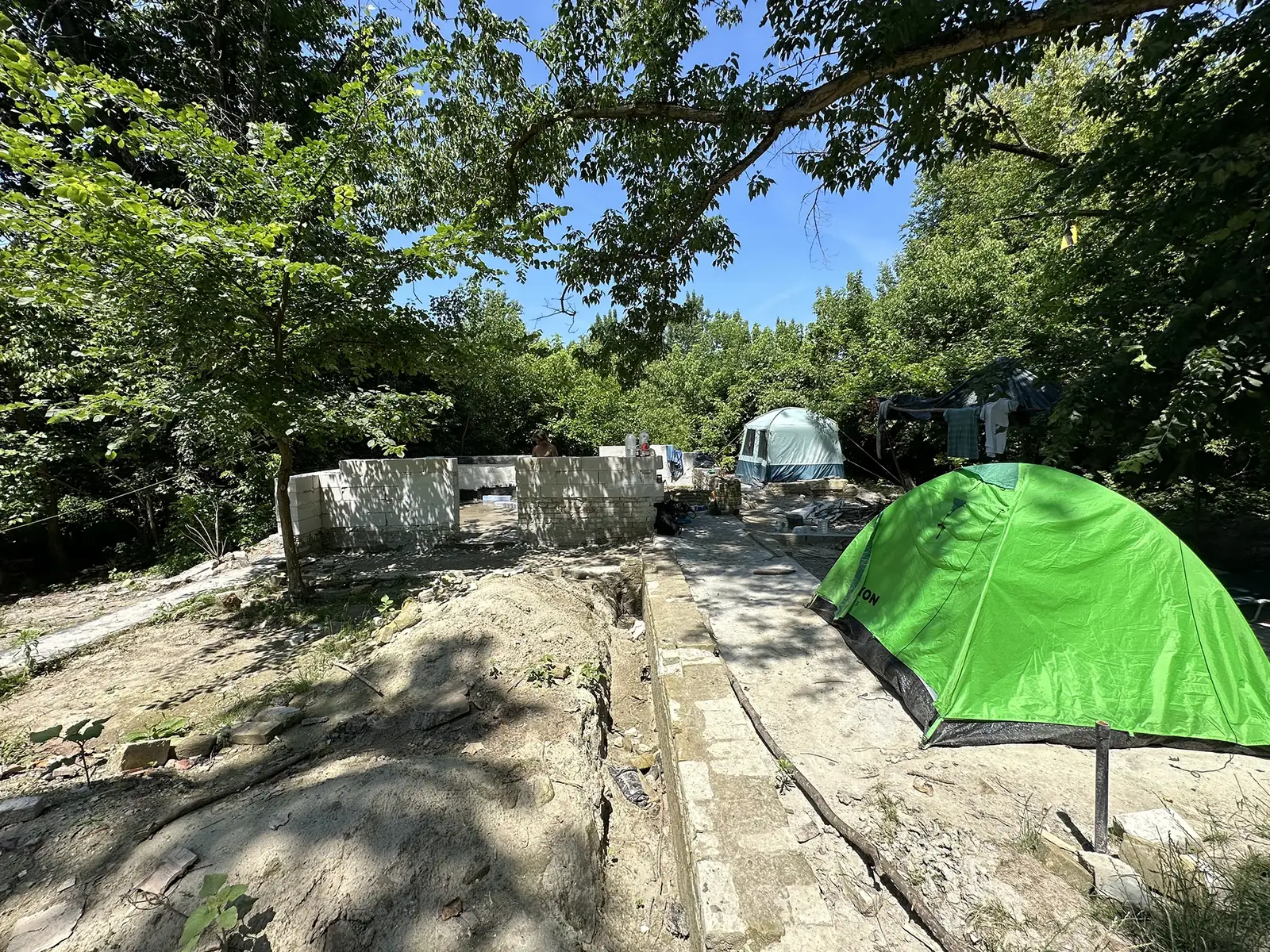 Settlers’ camp in Liberland: tents beside the first house under construction in the Danube floodplain forest