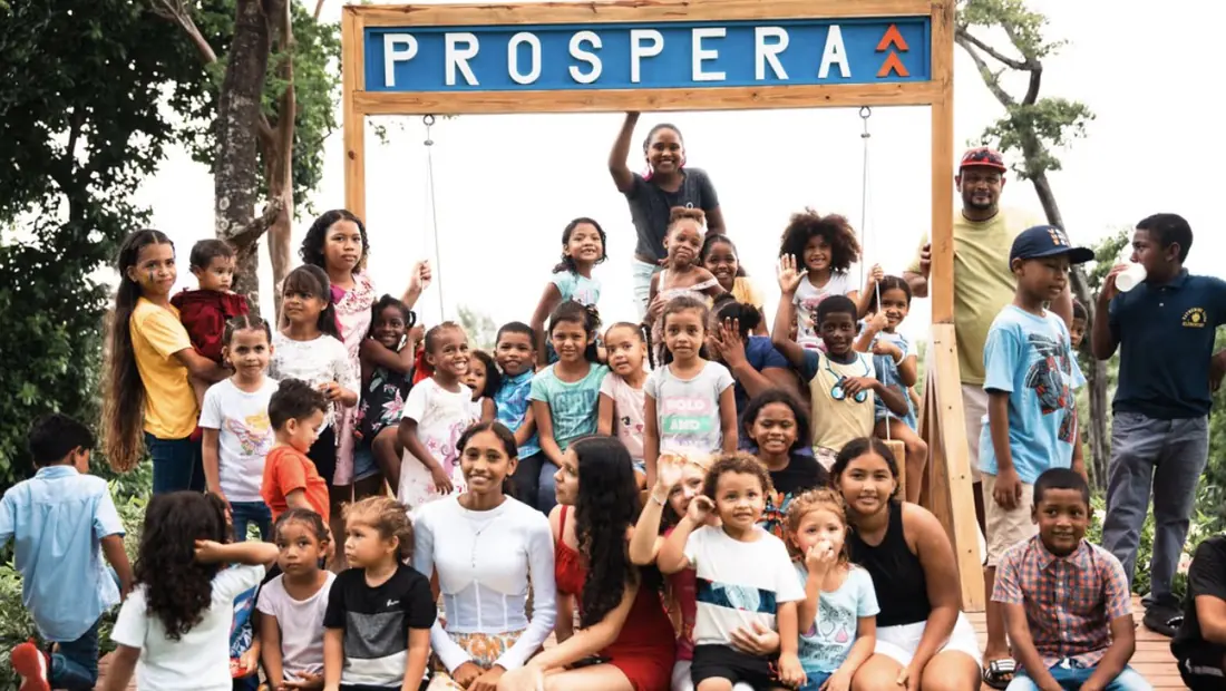 Children and families gathered under the Próspera sign on Roatán