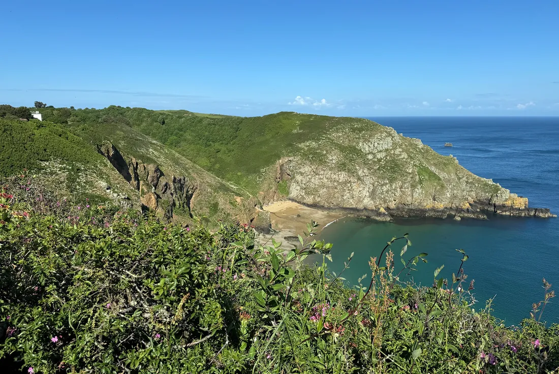 Sark’s cliffs above a sheltered sandy bay with clear turquoise water